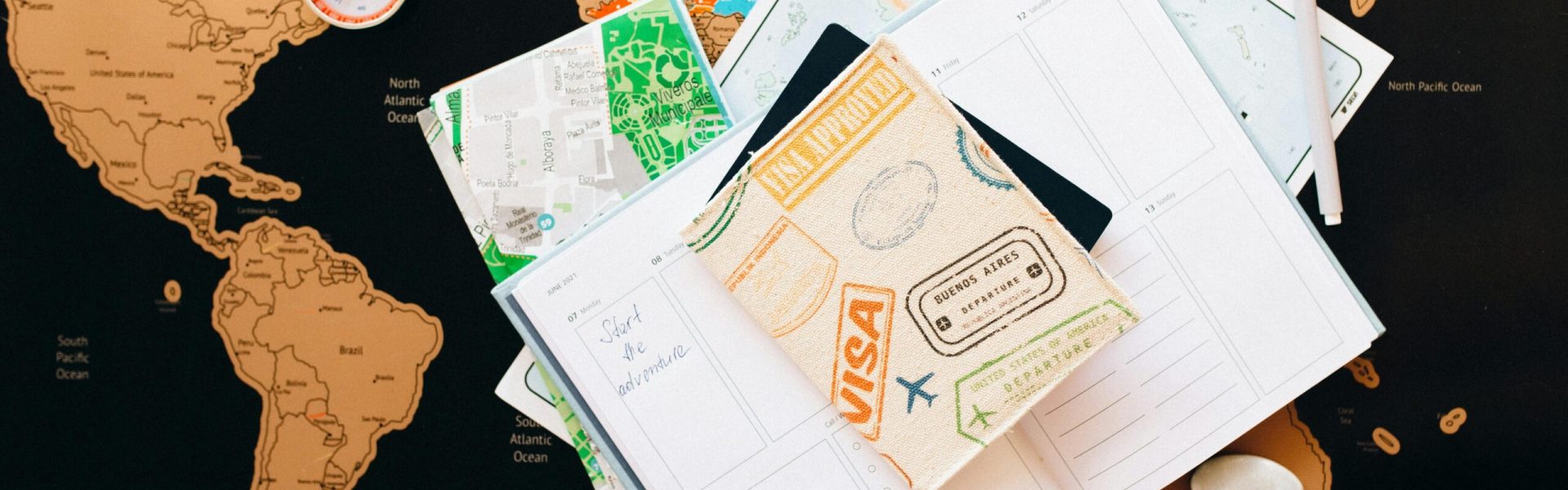 A flat lay of travel planning items on a map, featuring a compass, notebook, and guide for wanderlust enthusiasts.